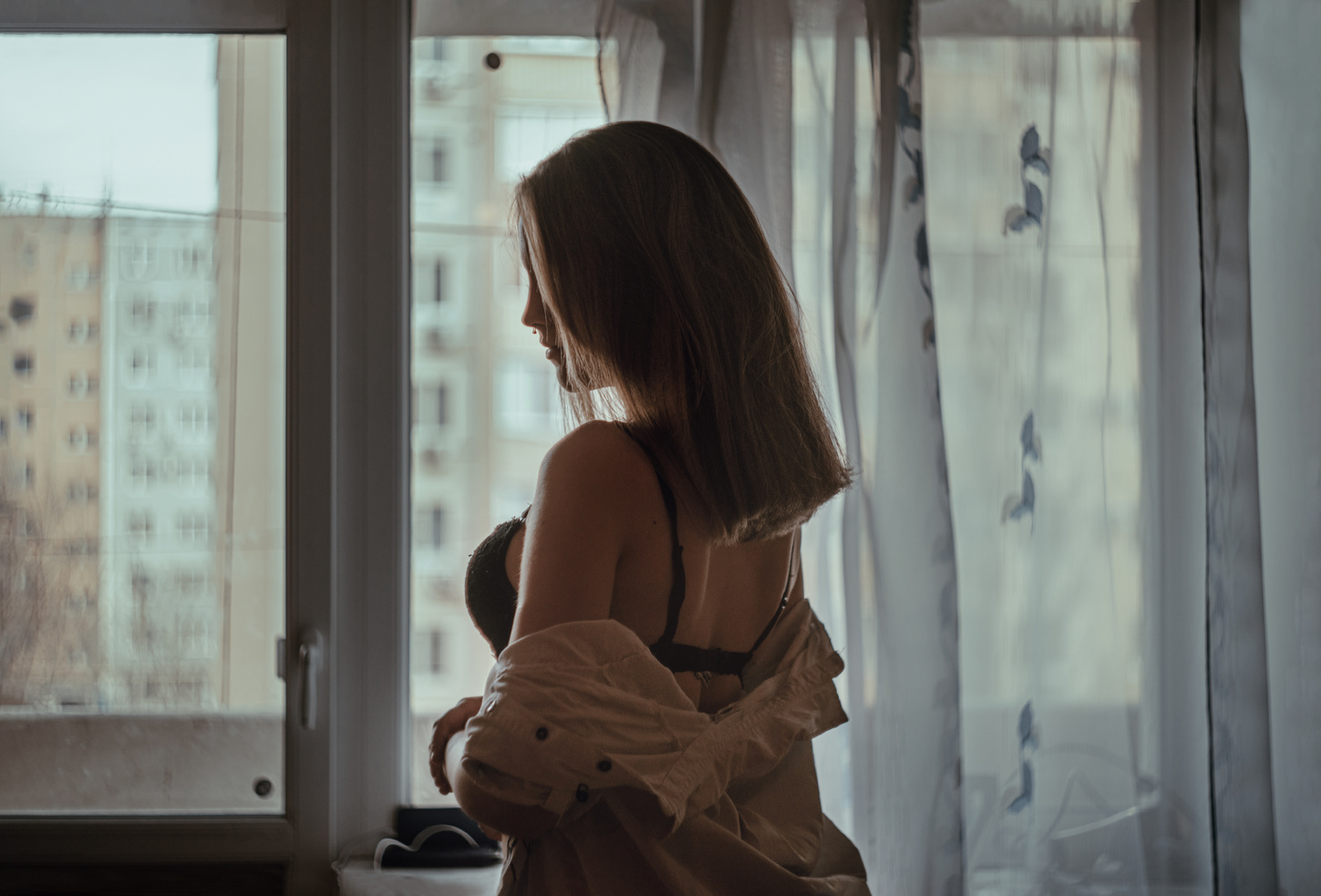 Photo of a Woman with a Brassiere Standing Near a Window